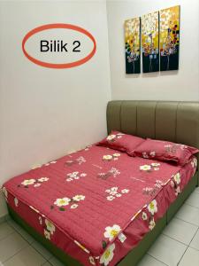 a bed with a red bedspread with flowers on it at HOMESTAY CIKGU NORa near UTHM KPTM KKTM IPG Moslim onli in Kampong Seri Gading