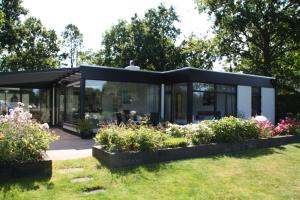 een glazen huis in een tuin met bloemen bij OPt7 in Arnemuiden