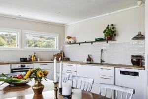 eine Küche mit weißen Schränken und einem Tisch mit einer Schale Obst in der Unterkunft Family Cabin With A View in Mandal