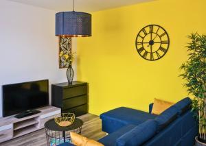 een woonkamer met een blauwe bank en een klok bij Appartement Centre Saint-Omer, Parking privé gratuit in Saint-Omer