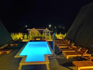 a swimming pool at night with a group of chairs at A frame Alba Iulia in Alba Iulia