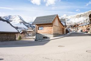 ein Holzhaus in einer Straße mit Bergen im Hintergrund in der Unterkunft Chalet Saint Sorlin in Saint-Sorlin-dʼArves
