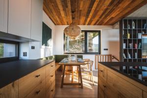 a kitchen with a wooden ceiling and a table with chairs at Chalet Paseka in Pec pod Sněžkou