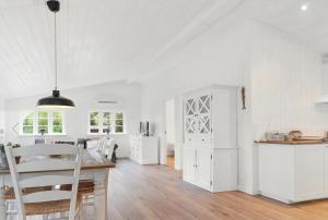 a kitchen and living room with white cabinets and a table at Beach House Near Sejerø Bay in Hønsinge