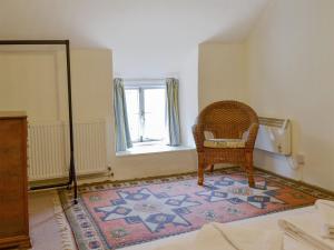 einen Stuhl auf einem Teppich in einem Zimmer mit Fenster in der Unterkunft Mulberry Cottage - 27905 in Langton Matravers