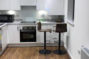 una cocina con armarios blancos y una silla. en Flat-Sleeps 4 & Direct links to Central London, en West Thurrock