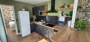 a kitchen with a white refrigerator and a wooden floor at L'Espadon in Luc-sur-Mer