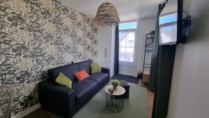 a living room with a blue couch and a table at L'Espadon in Luc-sur-Mer