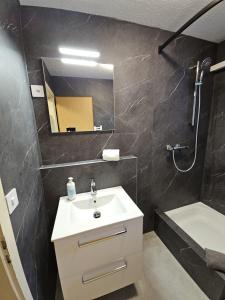un bagno con un lavandino, uno specchio e una vasca di Lauberhorn Apartment - Aare Jungfrau AG a Grindelwald