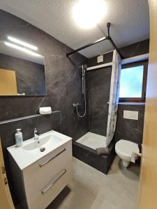 un bagno con lavandino, doccia e WC di Lauberhorn Apartment - Aare Jungfrau AG a Grindelwald