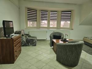 ein Wohnzimmer mit Fernseher und Tisch und Stühlen in der Unterkunft Relax Thermal Villapark Csokonyavisonta fürdőbelépővel in Csokonyavisonta