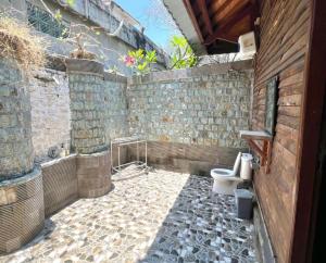 a bathroom with a toilet and a stone wall at Bronze Bungalow in Gili Meno