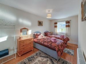 ein Schlafzimmer mit einem Bett, einer Kommode und einem Spiegel in der Unterkunft Ballygroggan Cottage - Uk48768 in Machrihanish + 7 Fotos