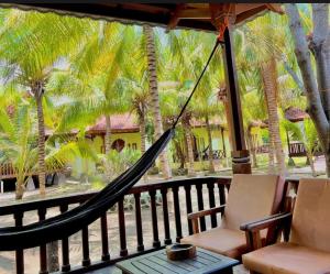 a hammock on the porch of a resort with palm trees at Bronze Bungalow in Gili Meno