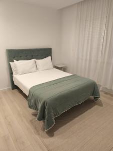 une chambre avec un lit avec une couverture verte dessus dans l'établissement Morden Spacious Apartment, à Entroncamento