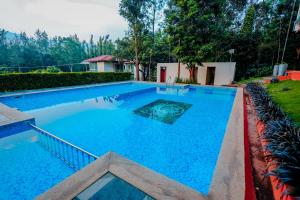 a large swimming pool with blue water in a yard at The Nature's Nest in Attigundi