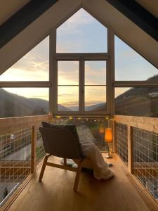 een kamer met een stoel voor een groot raam bij Mosel Chalets - Design-Ferienhäuser mit Sauna & Weinblick in Pommern - Direkt am Weinberg in Pommern