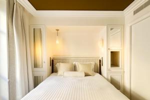 a bedroom with a bed with white sheets and pillows at Hôtel Almarine Eiffel by Malone in Paris