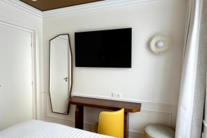 パリにあるHôtel Almarine Eiffel by Maloneのベッドルーム(鏡、壁掛けテレビ付)