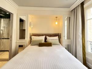 a bedroom with a large white bed with two pillows at Hôtel Almarine Eiffel by Malone in Paris