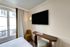 パリにあるHôtel Almarine Eiffel by Maloneのデスク、壁掛けテレビが備わるホテルルームです。