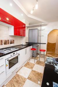 una cucina con armadi rossi e 2 sgabelli rossi di Центр. Хмельницького. 2 спальні a Ternopilʼ
