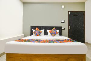 a bedroom with a large bed with colorful pillows at FabHotel Paradise Inn in Indore