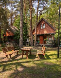 ein Picknicktisch und Bänke vor einem Haus in der Unterkunft Domki letniskowe BAŁTYK in Łeba