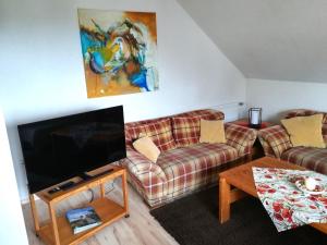 een woonkamer met twee banken en een flatscreen-tv bij Ferienwohnungen Ingrid Alfes in Ernestus