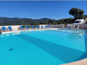 セラ・ディ・フェロにあるMini-villa en pierre avec vue natureの青い椅子と山のある大きなプール