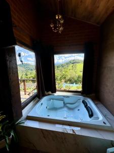 una vasca da bagno in una stanza con una finestra di Chale Da Terra Brasil, Piscina, Hidro dupla, lareira, vista espetacular a Santo Antônio do Pinhal