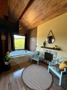 un bagno con vasca e una grande finestra di Chale Da Terra Brasil, Piscina, Hidro dupla, lareira, vista espetacular a Santo Antônio do Pinhal Altre 93 foto