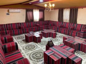 een grote woonkamer met rode banken en tafels bij Bedouin Village Hostel in Wadi Rum