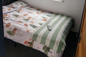 Una cama con una manta con mando a distancia. en Cabin at Animal Rescue Sanctuary - Sleeps 2, en Newchurch