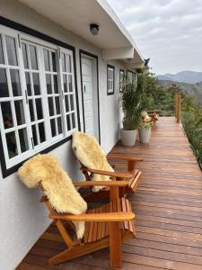 a wooden deck with two chairs with furry cushions on it at Suites da Dani in Areal +9 photos