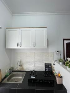 a kitchen with a stove and a sink and white cabinets at Casa de Brisa BnB in Prampuan