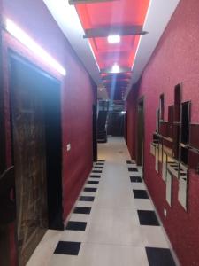 ein Flur mit roten Wänden und schwarz-weißen Fliesenböden in der Unterkunft Grand Orchard One Hotel in Lahore