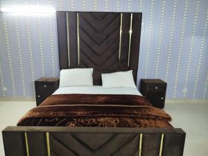 ein Bett mit einem hölzernen Kopfteil in einem Zimmer in der Unterkunft Grand Orchard One Hotel in Lahore