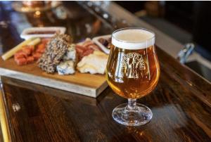 a glass of beer sitting on a table with a plate of food at Hotel Bishops Arms Piteå in Piteå