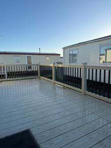 een houten terras met een hek en een gebouw bij Sam's Caravan Hire Coastfield Holiday Village Ingoldmells in Ingoldmells