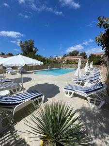 un gruppo di sedie e ombrelloni accanto a una piscina di Le Râteau Bavoir a Calvi