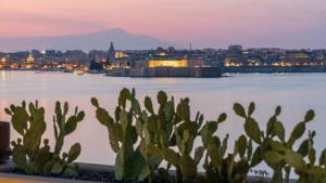a view of a city and the water at night at Minareto in Siracusa