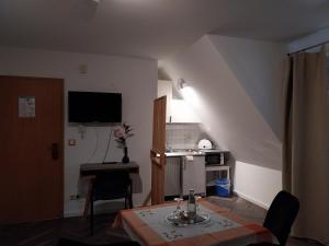 a living room with a table and a desk with a television at Gästehaus Langhammer in Bubenreuth