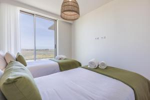two beds in a room with a large window at Bayline XV in Armação de Pêra