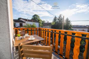 Una mesa de madera sentada en un balcón con una mesa. en Spacious Apartment Senozece - with terrace & grill, en Senožeče