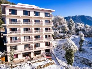 a building with snow on the ground and trees at The Radiance - kurfi in Chail