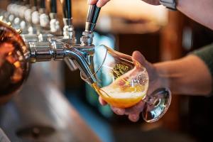 a person is pouring a glass of beer at Hotel Bishops Arms Köping in Köping