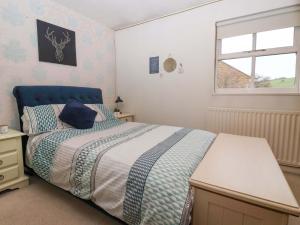 a bedroom with a bed with a blue headboard and a window at Lair Close House in Harrogate
