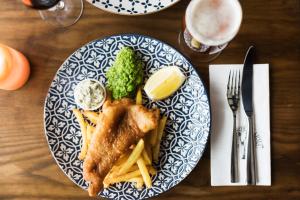 a plate of food with fish and fries on a table at Hotel Bishops Arms Köping in Köping