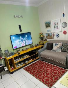 een woonkamer met een bank en een flatscreen-tv bij Quarto Suite Barra Réveillon Salvador in Salvador